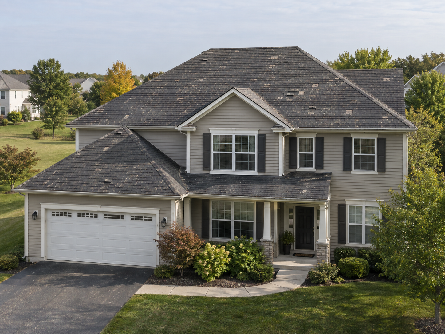 A gray-sided two-story Illinois home, hail-damaged roof